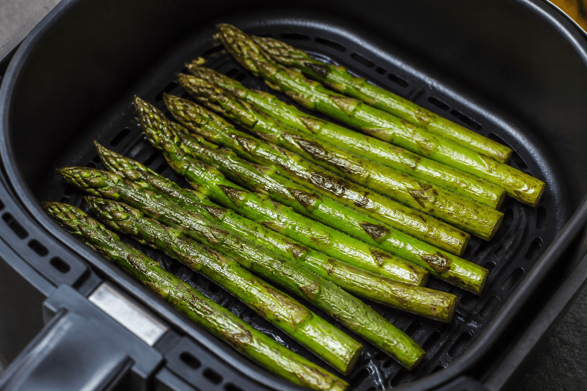 Green asparagus spears in the air fryer basket