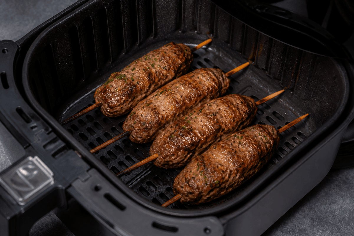 Lamb kofta skewers browning in the air fryer basket