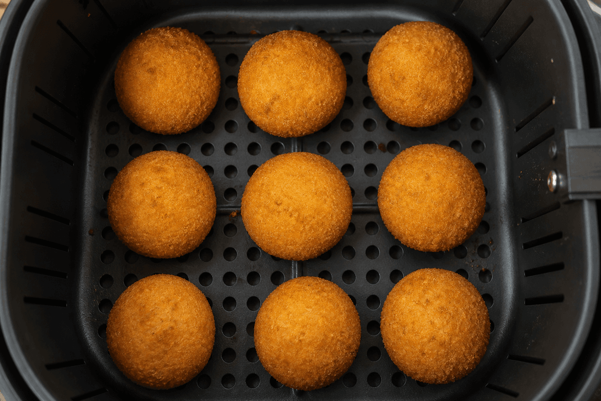 Round breaded fish cutlets in the air fryer basket