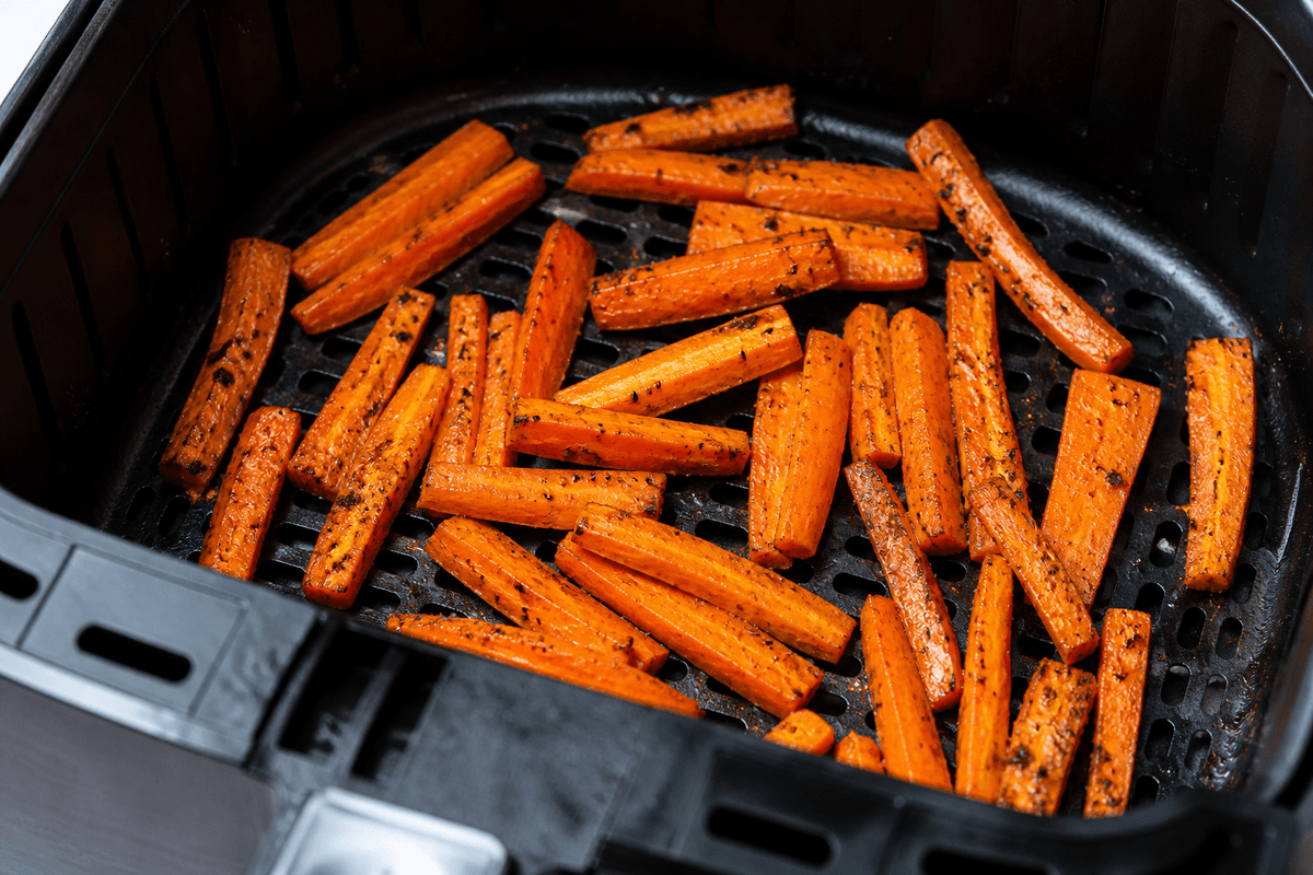 Golden carrot sticks cooking in the air fryer basket