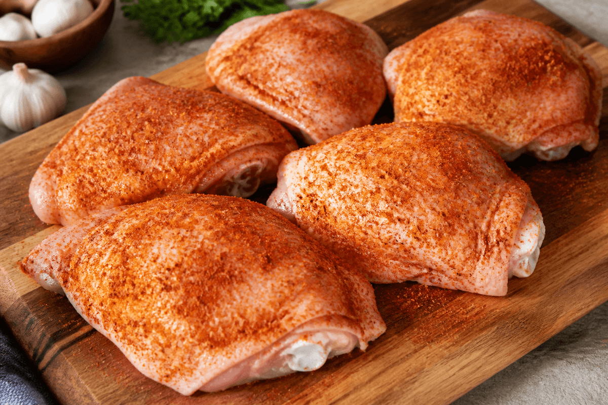 Seasoned bone-in chicken thighs on a board