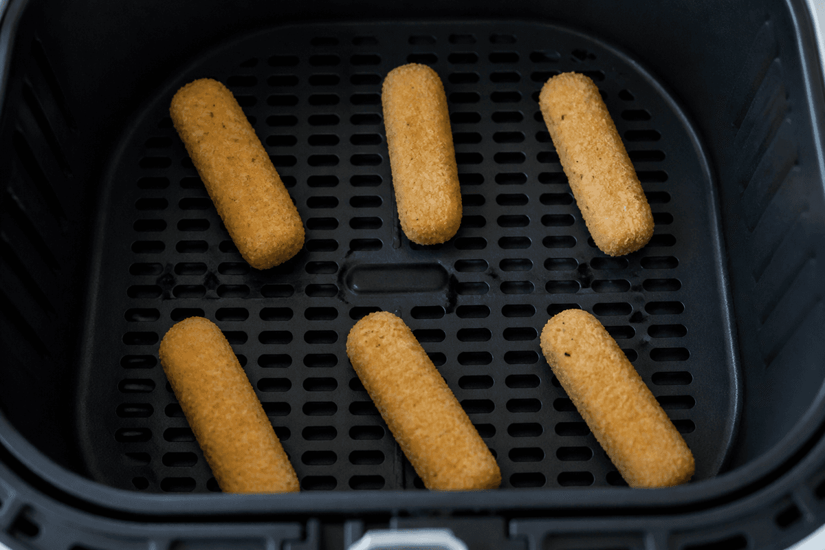 Breaded mozzarella sticks spaced in the air fryer basket
