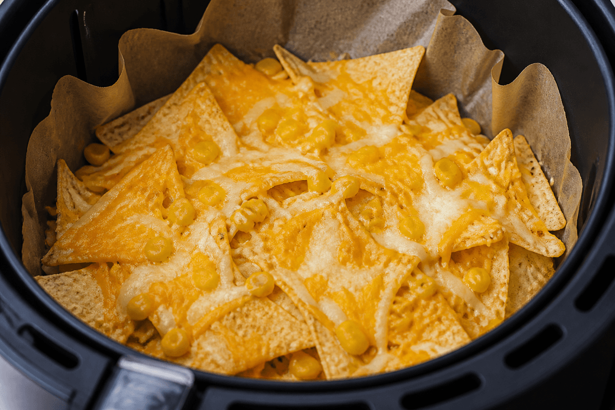 Tortilla chips layered with cheese and corn in the air fryer basket