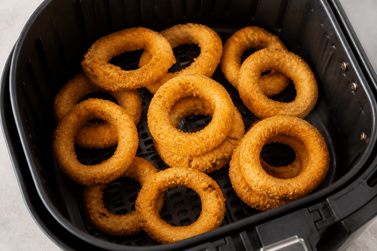 Golden onion rings cooking in the air fryer basket