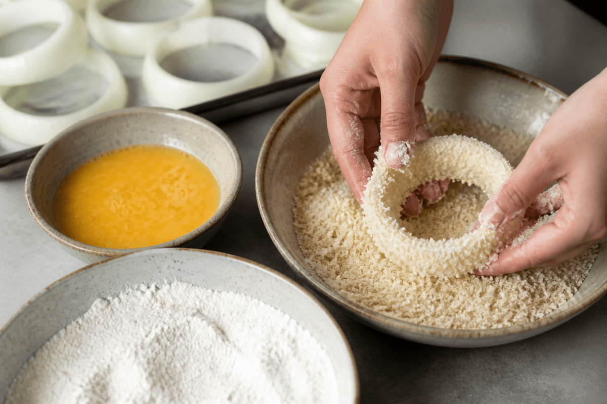 Onion rings being coated in panko breadcrumbs