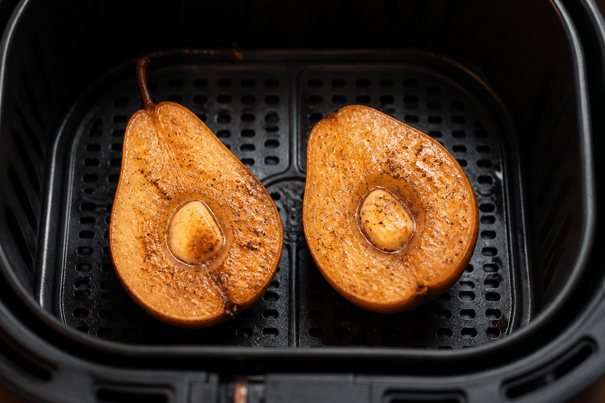Caramelized pear halves cooking in the air fryer basket
