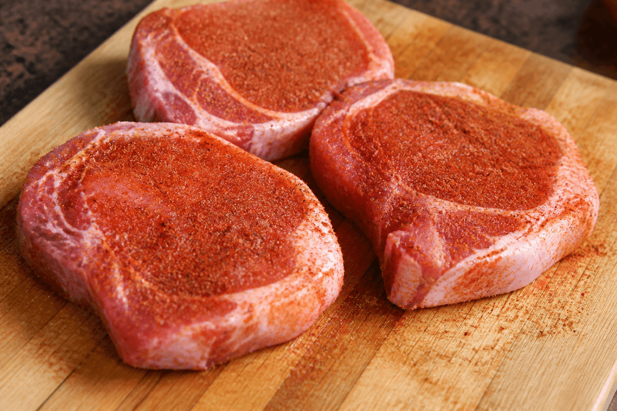 Pork chops rubbed with spice seasoning on a board