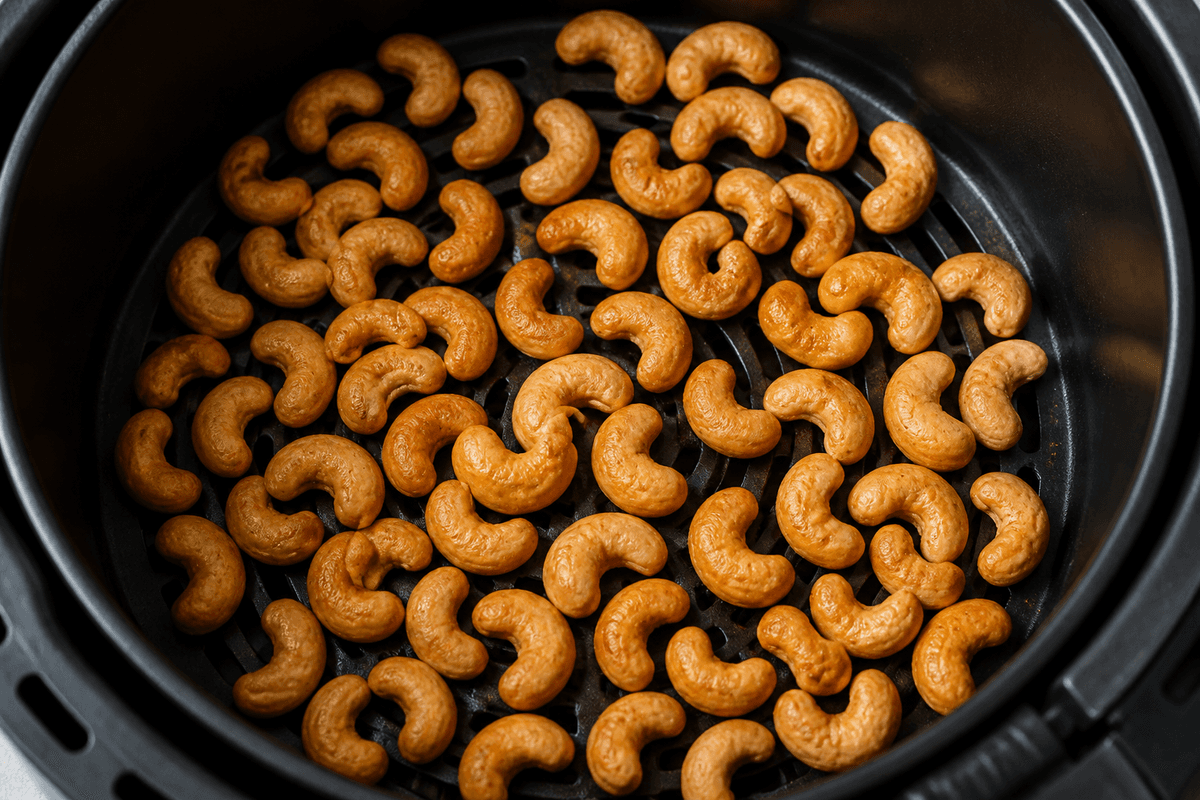 Oil-coated cashews roasting in the air fryer basket